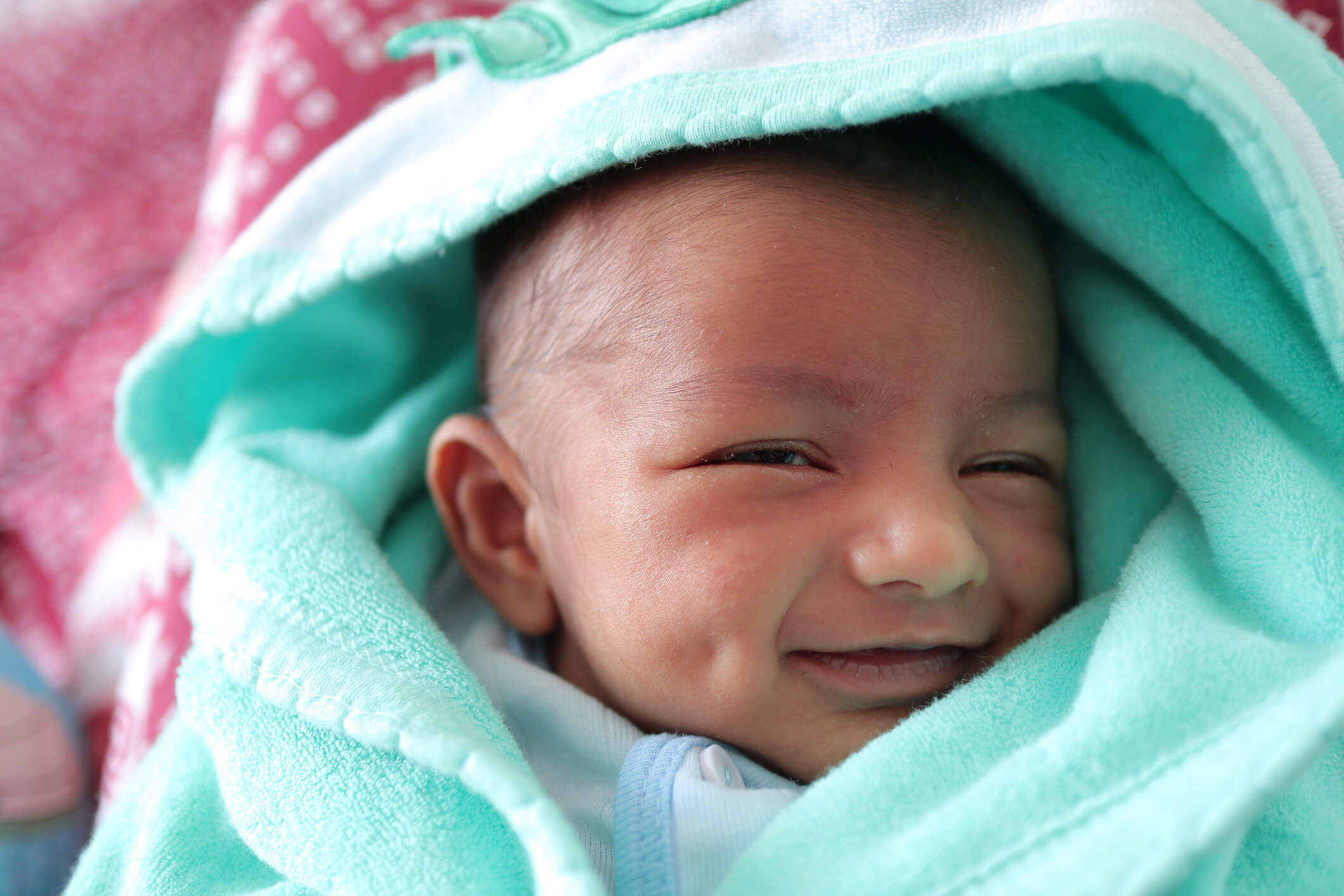 Smiling baby wrapped in blanket looks at camera